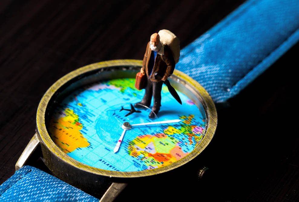 concept of an old man standing on a watch with a map of the worl on it