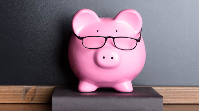 Piggy Bank With Eye Glasses On Book