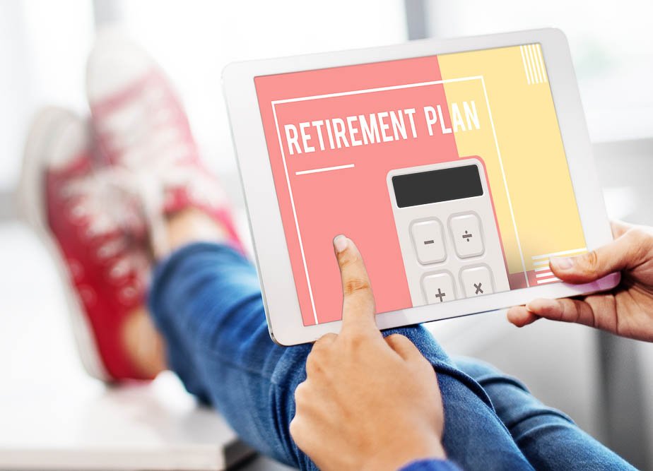person sitting on at a desk with their feet up looking at a tablet that states retirement plan